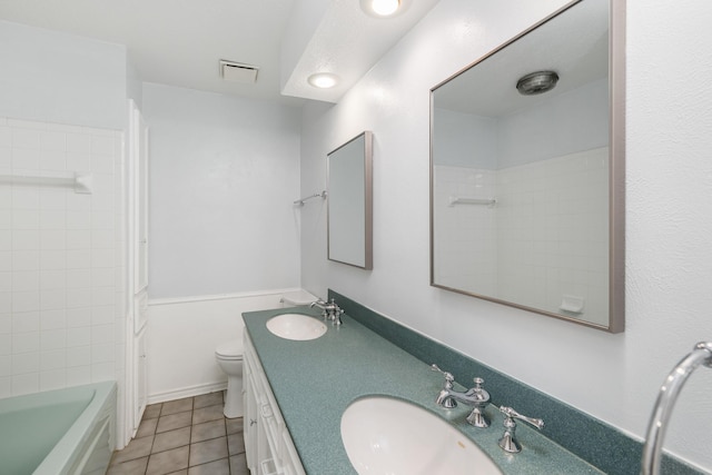 full bathroom featuring tile patterned flooring, vanity, tiled shower / bath, and toilet