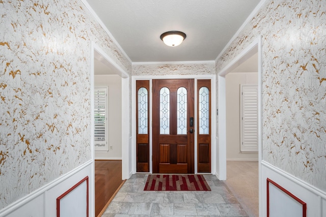 entrance foyer with ornamental molding and a textured ceiling