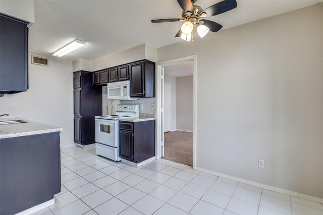 kitchen featuring white appliances, a ceiling fan, baseboards, a sink, and light tile patterned floors