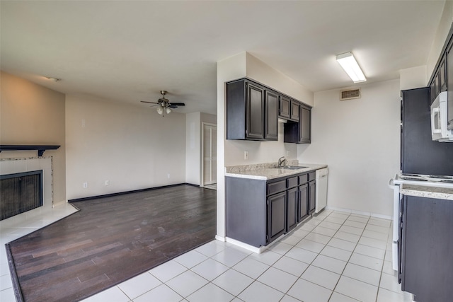 kitchen featuring open floor plan, white appliances, a ceiling fan, a sink, and light countertops