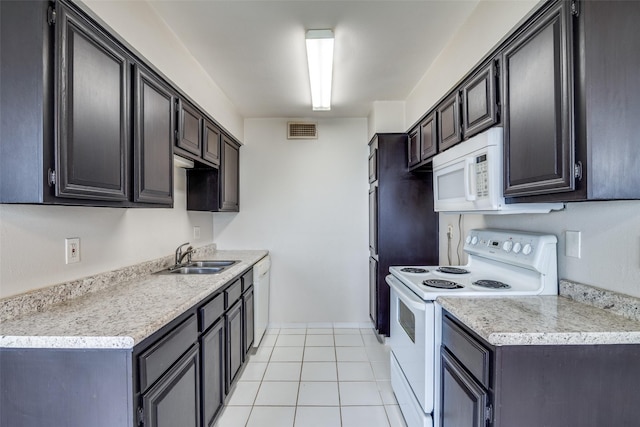 kitchen featuring white appliances, a sink, light countertops, and light tile patterned floors
