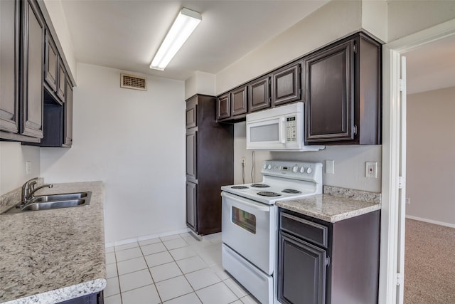 kitchen with white appliances, a sink, dark brown cabinetry, light countertops, and baseboards
