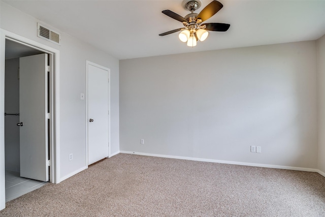carpeted spare room featuring a ceiling fan and baseboards