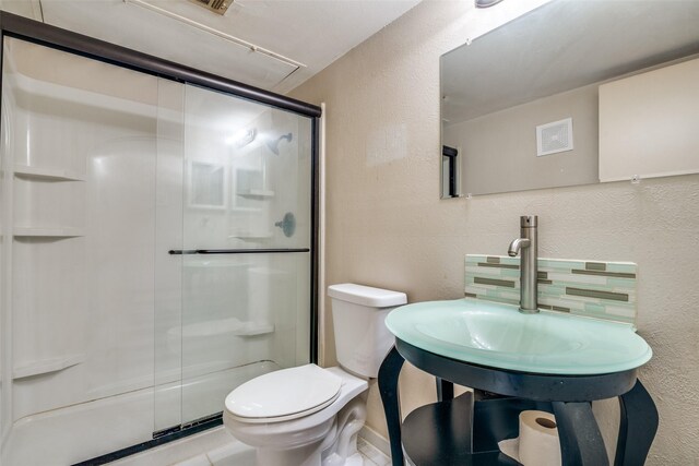 full bathroom with a textured wall, toilet, and a shower stall