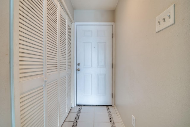 doorway with tile patterned floors and baseboards