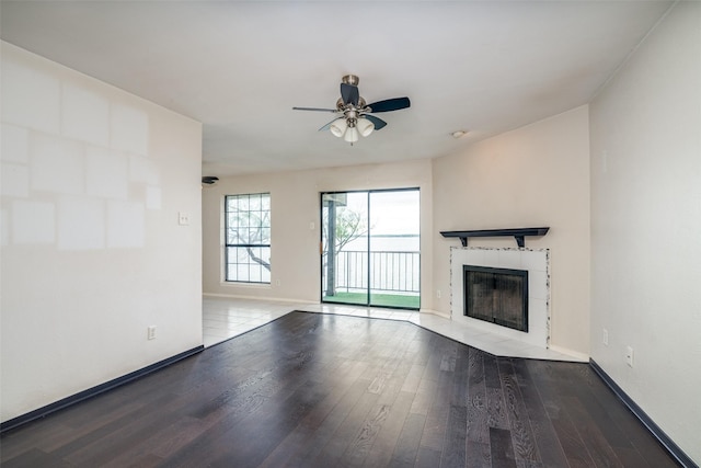 unfurnished living room featuring baseboards, wood finished floors, a ceiling fan, and a fireplace