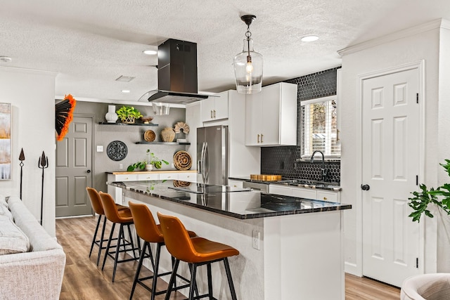 kitchen with island range hood, decorative light fixtures, white cabinetry, a center island, and stainless steel appliances