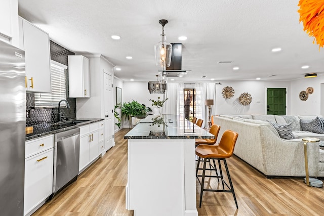 kitchen featuring sink, white cabinetry, hanging light fixtures, appliances with stainless steel finishes, and a kitchen island