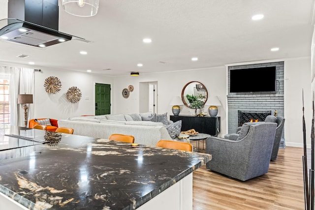 kitchen with ventilation hood, a fireplace, and light hardwood / wood-style floors