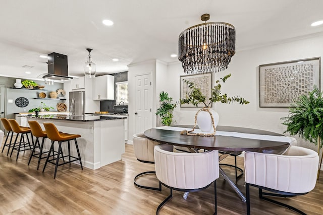 dining room featuring ornamental molding, a chandelier, and light wood-type flooring