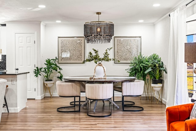 dining space with crown molding, light hardwood / wood-style flooring, an inviting chandelier, and breakfast area