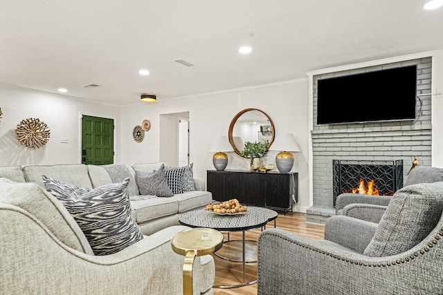 living room with hardwood / wood-style flooring, a fireplace, and ornamental molding