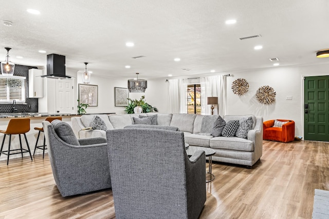 living room featuring sink, light hardwood / wood-style flooring, and a textured ceiling