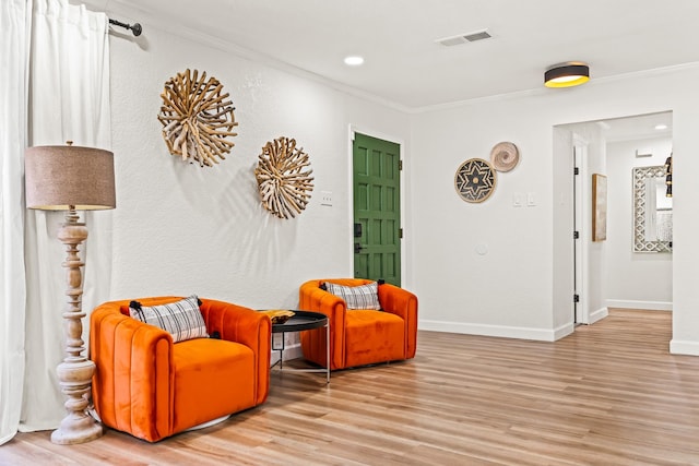 living area featuring crown molding and light wood-type flooring