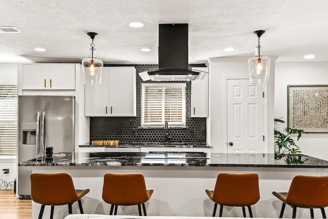 kitchen featuring white cabinetry, pendant lighting, island range hood, and backsplash