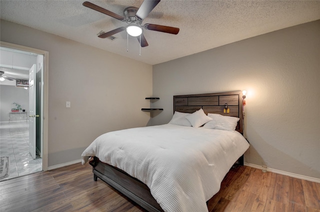 bedroom with ceiling fan, dark hardwood / wood-style floors, and a textured ceiling