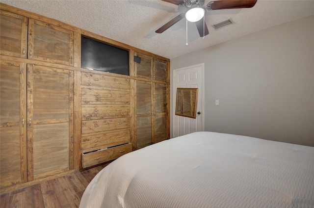 bedroom with hardwood / wood-style flooring, ceiling fan, and a textured ceiling