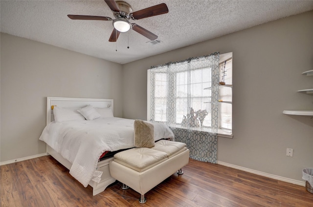 bedroom with ceiling fan, dark hardwood / wood-style floors, and a textured ceiling