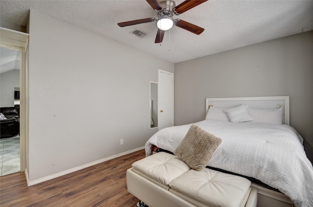 bedroom with hardwood / wood-style floors, a textured ceiling, and ceiling fan