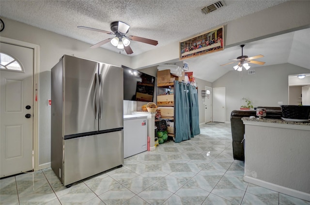 kitchen with ceiling fan, stainless steel fridge, a textured ceiling, and vaulted ceiling