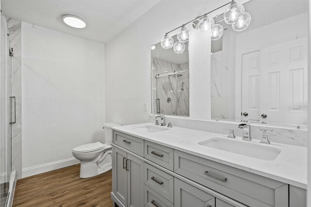 bathroom featuring hardwood / wood-style flooring, vanity, toilet, and a shower with door