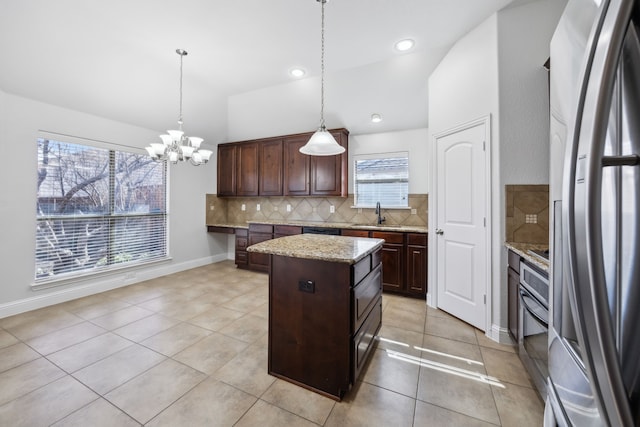 kitchen featuring tasteful backsplash, a center island, dark brown cabinets, hanging light fixtures, and stainless steel appliances