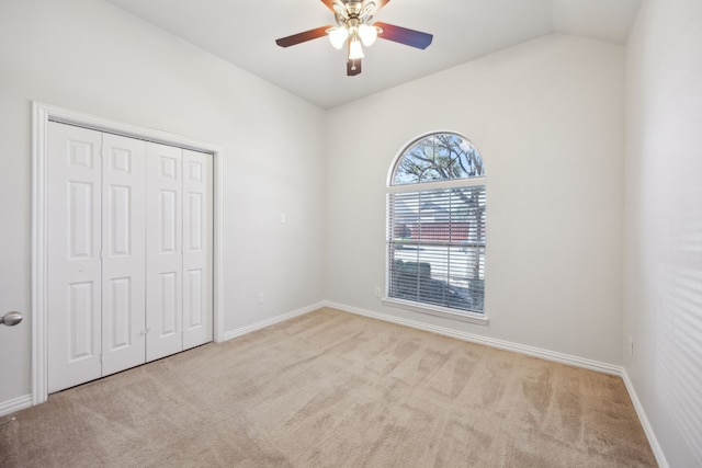 unfurnished bedroom with lofted ceiling, light colored carpet, a closet, and ceiling fan