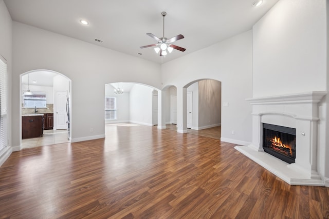 unfurnished living room with hardwood / wood-style flooring, ceiling fan, and a high ceiling