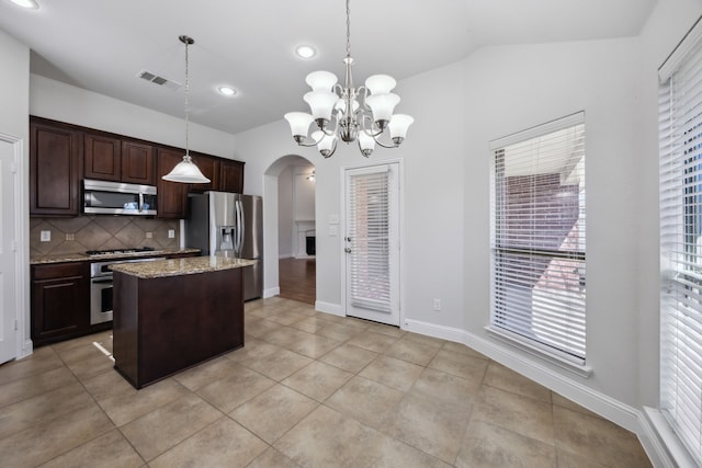 kitchen with dark brown cabinetry, light stone counters, decorative light fixtures, a center island, and stainless steel appliances