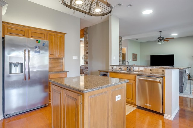 kitchen featuring a kitchen island, appliances with stainless steel finishes, sink, kitchen peninsula, and light hardwood / wood-style flooring