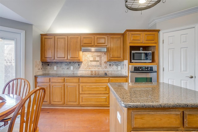 kitchen featuring lofted ceiling, stainless steel appliances, a center island, and light wood-type flooring