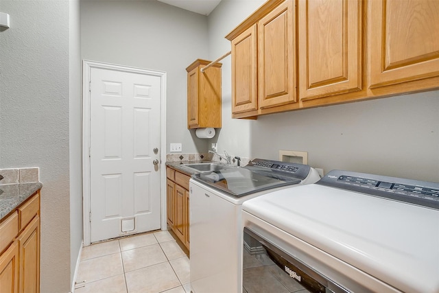 washroom with cabinets, sink, light tile patterned floors, and washing machine and clothes dryer