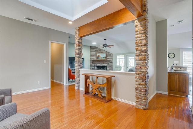 living room with hardwood / wood-style flooring, a healthy amount of sunlight, a stone fireplace, and decorative columns