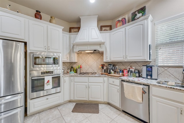 kitchen featuring white cabinetry, stainless steel appliances, and custom exhaust hood