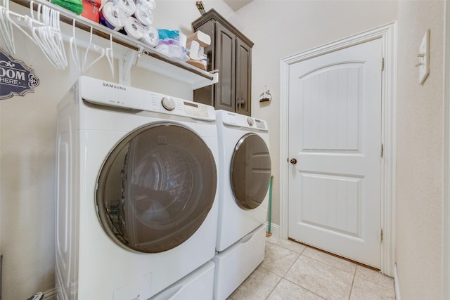 laundry area featuring light tile patterned floors, washer and clothes dryer, and cabinets