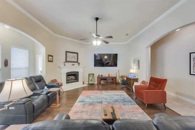 living room with crown molding, ceiling fan, and dark wood-type flooring