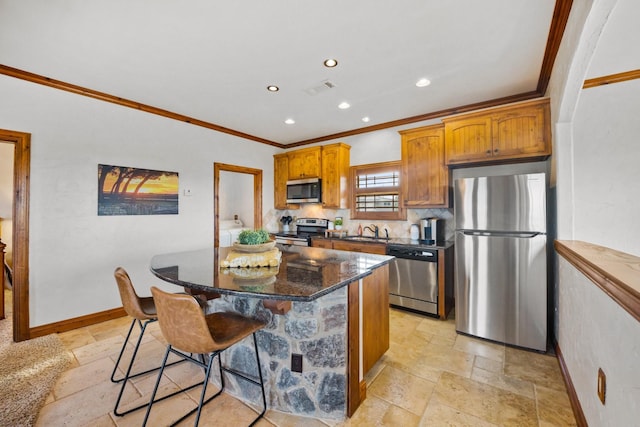 kitchen with a kitchen island, appliances with stainless steel finishes, sink, a breakfast bar area, and dark stone counters