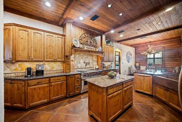 kitchen featuring beam ceiling, tasteful backsplash, a kitchen island, dark stone counters, and range with two ovens