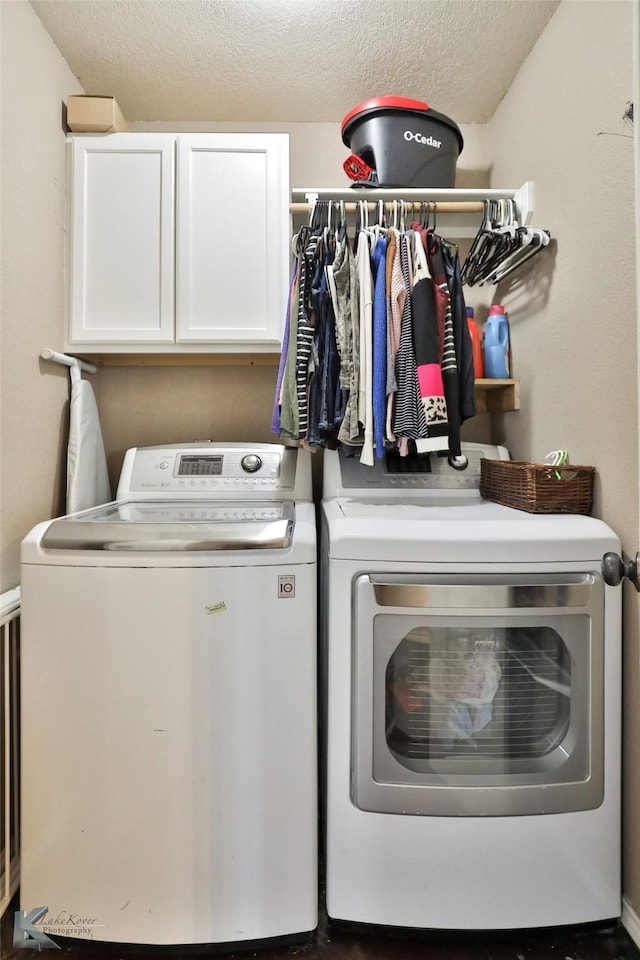 washroom featuring cabinets, a textured ceiling, and washing machine and clothes dryer