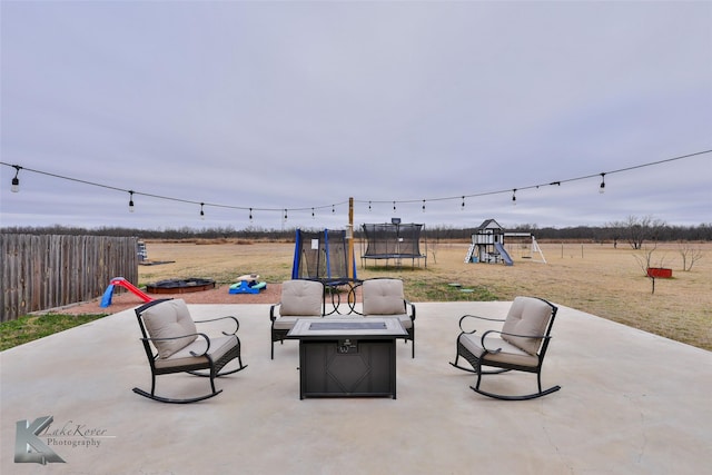 view of patio / terrace featuring an outdoor fire pit, a playground, and a trampoline