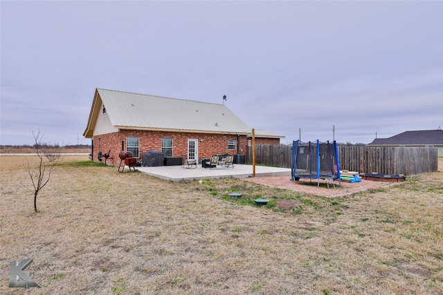 back of house with a patio, a yard, and a trampoline