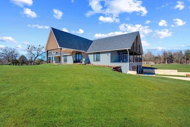 rear view of property with a hot tub and a lawn