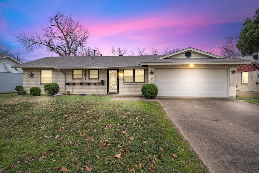 ranch-style house with a garage and a lawn