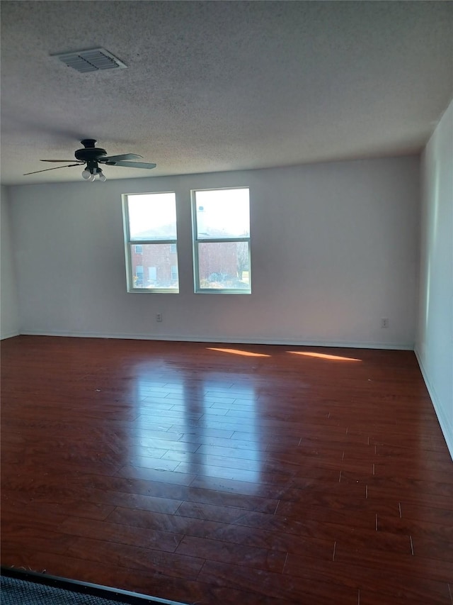 spare room with dark wood-type flooring, ceiling fan, and a textured ceiling