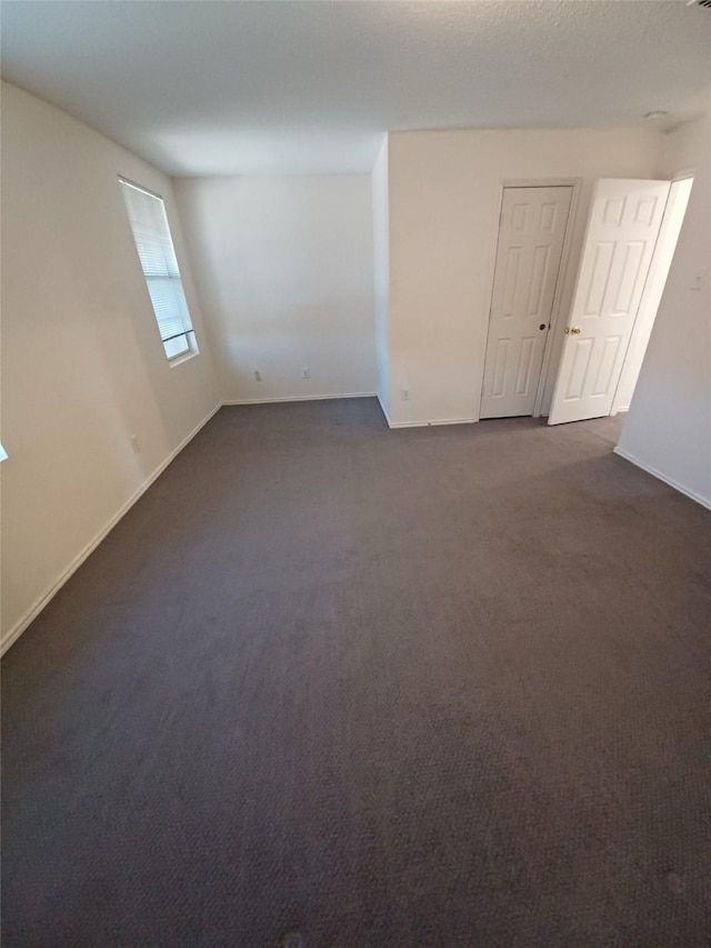 unfurnished room featuring a textured ceiling and dark colored carpet