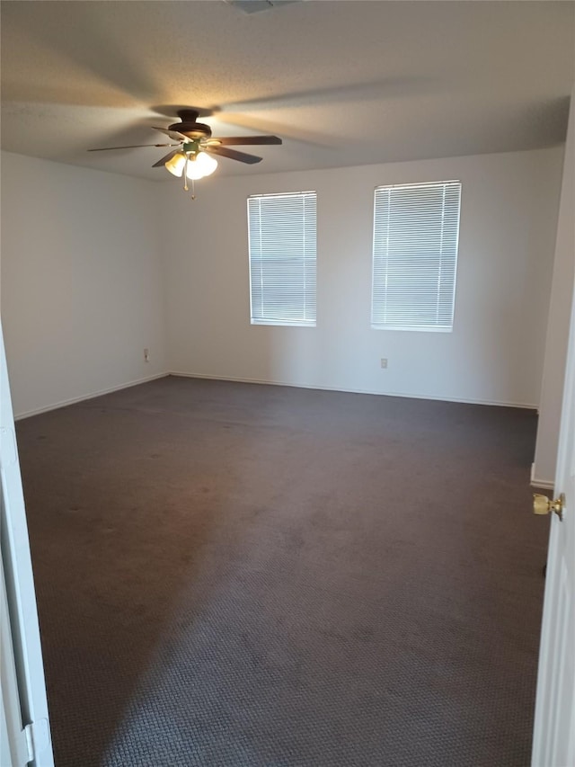 unfurnished room featuring ceiling fan and dark carpet