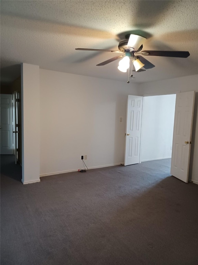 spare room featuring ceiling fan, dark carpet, and a textured ceiling