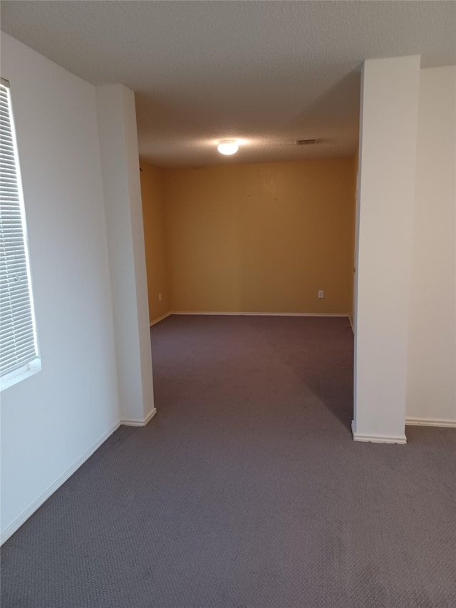 spare room with dark carpet and a textured ceiling