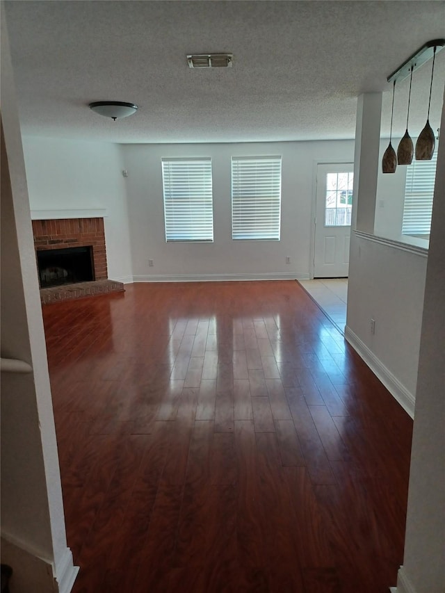 unfurnished living room with hardwood / wood-style flooring, a fireplace, and a textured ceiling