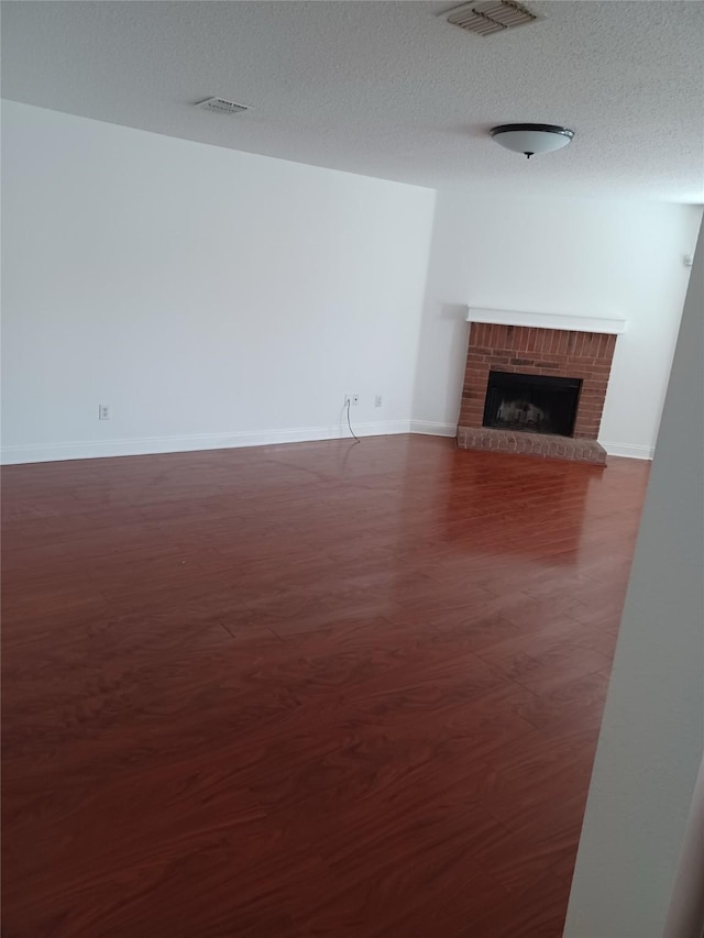 unfurnished living room featuring dark wood-type flooring, a fireplace, and a textured ceiling